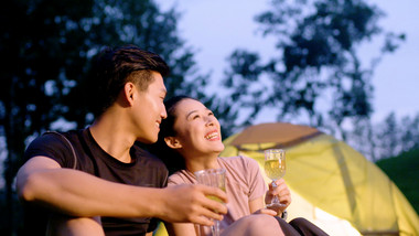 夜晚野餐开心饮酒的年轻情侣近景实拍