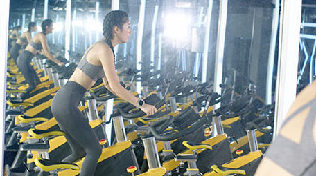 健身房动感单车运动的女子背影实拍