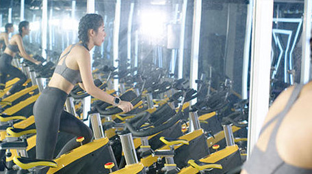 健身房动感单车运动的女子背影实拍