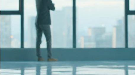 商务年轻男性走向窗边思考实拍