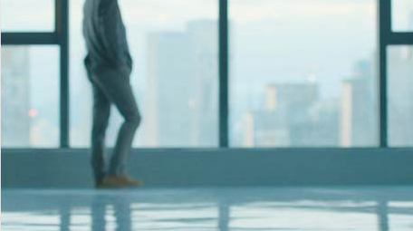 商务年轻男性走向窗边思考实拍