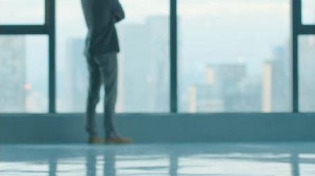 商务年轻男性走向窗边思考实拍