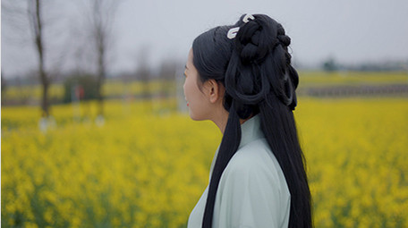 东方人像美女在菜花田中行走实拍