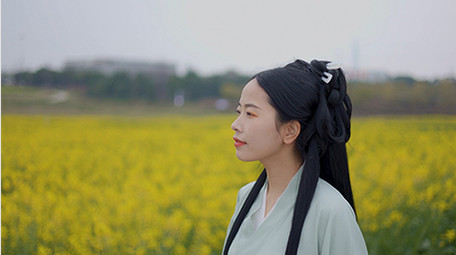 东方人像美女在菜花田中行走实拍