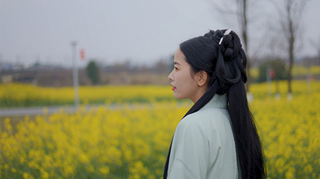 东方人像美女在菜花田中行走实拍