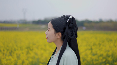 东方人像美女在菜花田中行走实拍