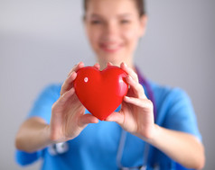 年轻的女医生抱着一颗红色的心，站在灰色的背景上