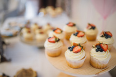 白色奶油蛋糕装饰着草莓和蓝莓的费用，在一个木制的盘子上