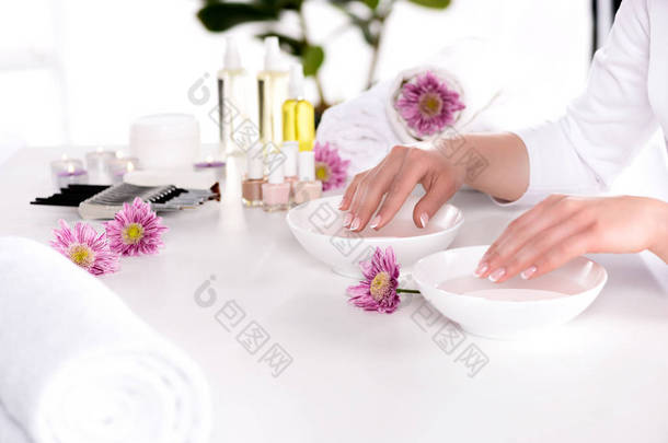 女性在餐桌上用鲜花、毛巾、蜡烛、芳香油瓶、指甲抛光、奶油容器和美容<strong>美发工具</strong>接收指甲的图像