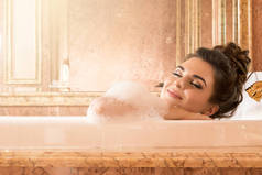 美丽的年轻妇女洗澡与泡沫在豪华公寓