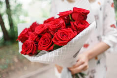 美丽的花束。年轻的女孩拿着鲜花安排与红玫瑰。花店的概念。目录的内容