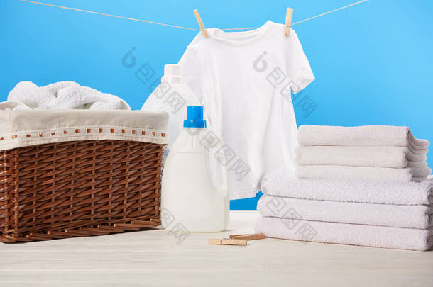 塑料容器, 装有洗衣液体、洗衣篮、一堆毛巾和挂在蓝色绳子上的干净的白色衣服