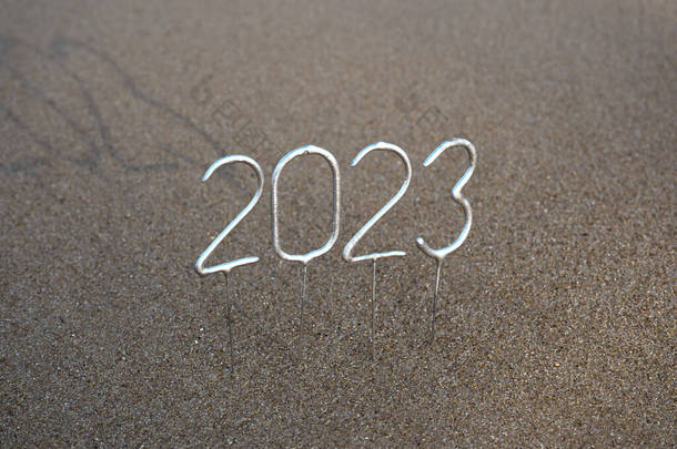即将到来的2023年新年在沙滩上的数字。异国情调的新年庆祝理念