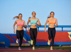 运动妇女组在田径竞赛跑道上运行