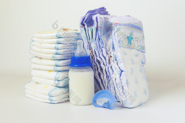 堆纸尿裤和白色背景上的婴儿奶瓶.