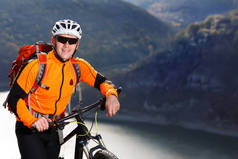 山地自行车橙色夹克站下了美丽的河流，抵制山.