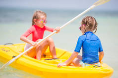 可爱的小女孩喜欢坐在黄色的皮划艇上划船