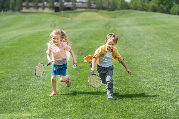 可爱的微笑<strong>儿童</strong>与<strong>羽毛球</strong>球拍一起跑在公园