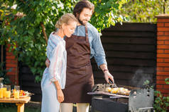 微笑的夫妇在后院烧烤在夏天天