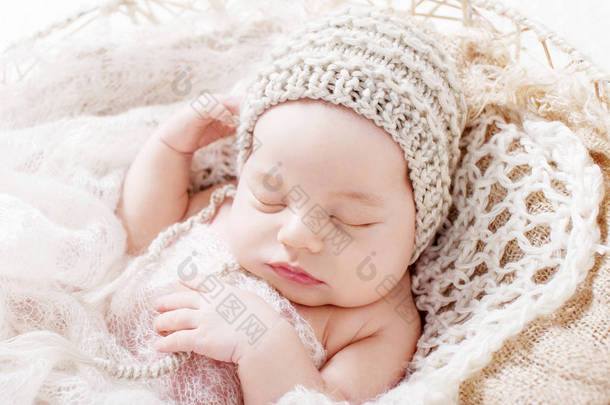 甜美的新生婴儿睡觉。3周大的新生男孩躺在篮子里用针织格子。漂亮的新生男孩的肖像。特写图像