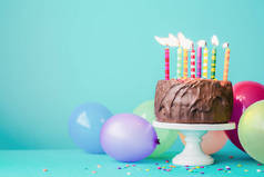 带彩色蜡烛和气球的巧克力生日蛋糕