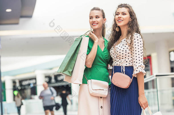美丽的微笑女孩拿着纸袋, 看着<strong>远离</strong>购物中心