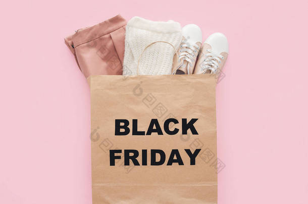 最热门的时尚服装在购物袋与黑色星期五标志被隔离粉红色