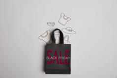 黑色购物袋的顶部视图与黑色星期五销售题词和纸衣服在灰色背景