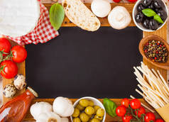 木炭木菜单板与自制的意大利面面食与鹌鹑蛋和奶酪在木背景。经典的意大利乡村美食。大蒜、香槟、黑橄榄和绿橄榄、木制铲子.