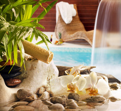 水疗概念与游泳池和日光浴浴床的石头兰花瀑布