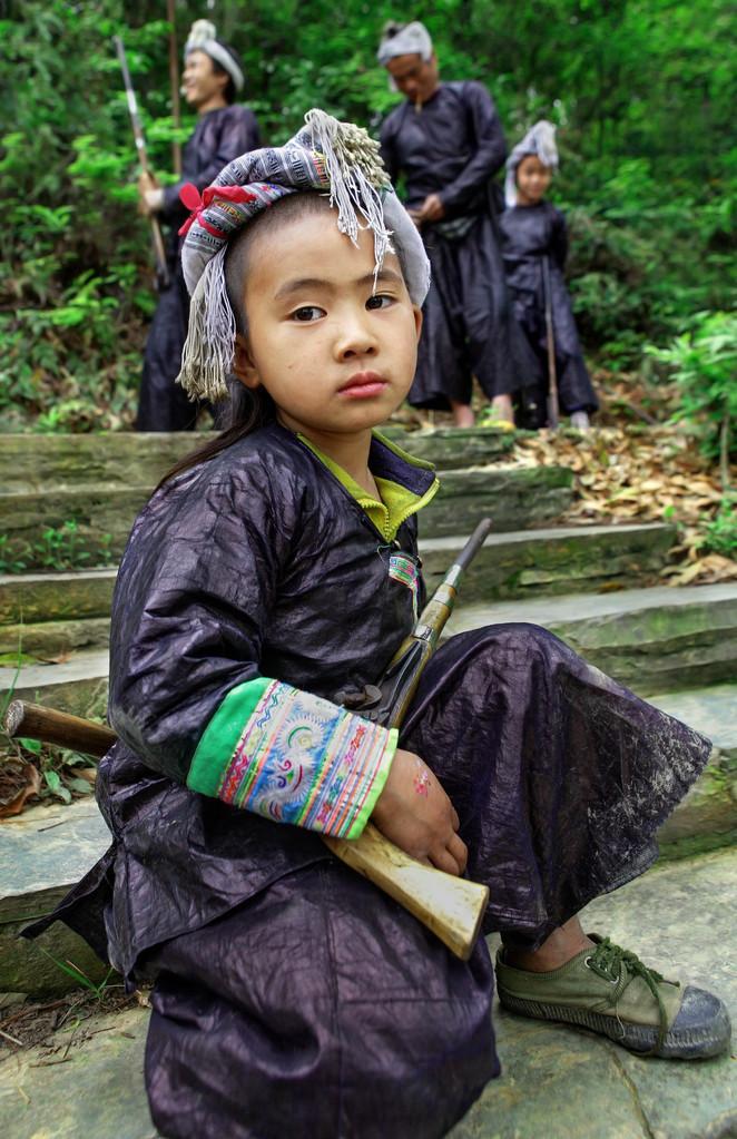 中国少年在传统民族服饰苗族部落武装与老滑