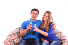 年轻夫妇坐在沙发上和饮用可口可乐饮料
