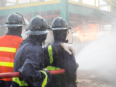 在训练期间与压力水灭火的消防队员。消防员喷涂直蒸汽进火了.