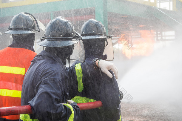 在训练期间与压力水<strong>灭火</strong>的<strong>消防队</strong>员。消防员喷涂直蒸汽进火了.