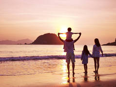 亚洲家庭在海滩上看日出