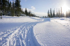 冬季景观与雪堆之间的滑雪道和夕阳.