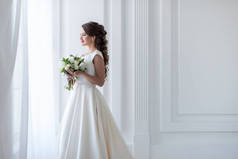 有魅力的新娘摆在传统礼服与婚礼花束