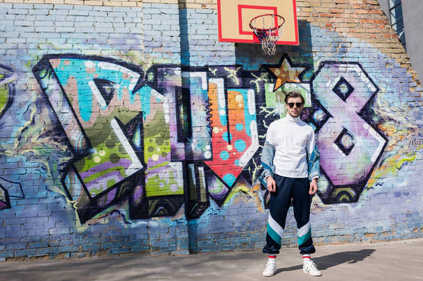 时尚的年轻男子在老式服装在砖墙前的<strong>涂鸦</strong>和<strong>篮球</strong>戒指