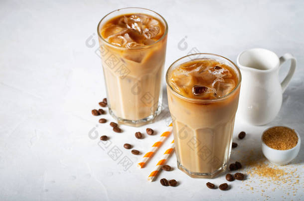 冰咖啡在一个高的玻璃与奶油倒在和咖啡豆。浅蓝色背景下的冷夏日饮品.