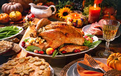 感恩节晚餐。用覆盆子装饰的烤火鸡，放在用南瓜、蔬菜、馅饼、鲜花和蜡烛装饰的乡村风格的桌子上