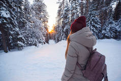 年轻的妇女与背包去冬天森林路在雪覆盖了冬天松树林。多雪的天气。大松。寒假