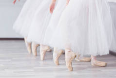 脚在尖。芭蕾学校的练习。芭蕾课。一群女孩站在一排, 伸出双腿, 在尖上滑行。孩子们穿着白色裙子。老师领导一个舞蹈课.