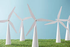 白色风车模型在蓝色背景和绿色草