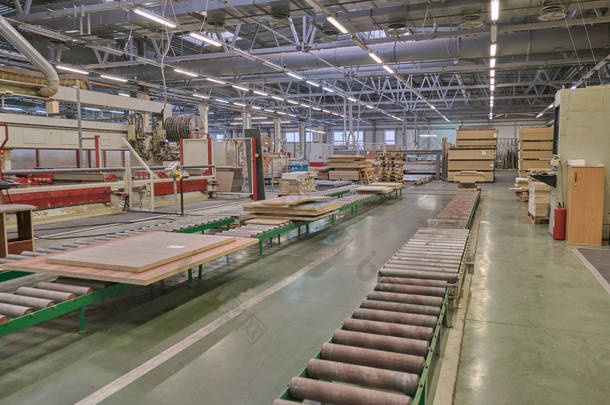 在某木工企业中铺设家具加工和生产用刨花板。一家家具厂的生产线。木材加工用铣床和锯床.