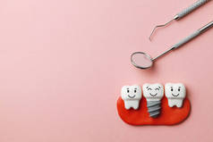 健康的白色牙齿和植入物微笑在粉红色的背景和牙医工具镜子, 钩子。复制文本的空间.