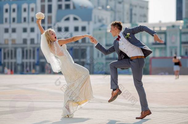 新娘和新郎在<strong>婚礼服</strong>装在镇广场上跳着火热的舞蹈