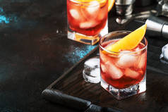 夏季酒精鸡尾酒 Negroni 与干杜松子酒, 红色苦艾酒和红色苦味, 橙片和冰块。棕色条形图计数器背景、条形工具、文本位置、选择性对焦