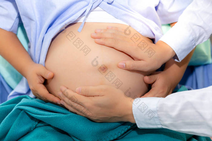 英俊的医生正在检查胎儿的位置通过触摸孕妇