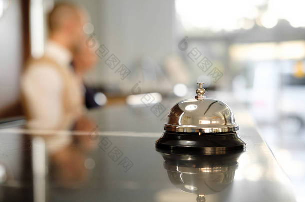 带贝尔的现代豪华酒店接待处柜台。服务钟定位在接待处。银叫响铃在桌上, 接待员在背景。见鬼在酒店里概念.