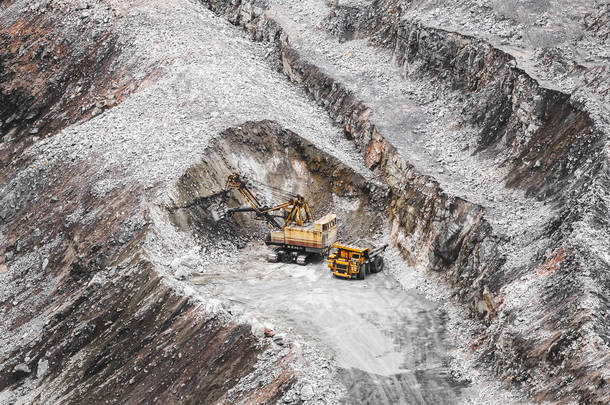 采石场内的大型橙色采矿卡车和挖掘机。铁矿石开采。重型采矿设备。从上看露天矿开采采石场提取铁石磁铁矿